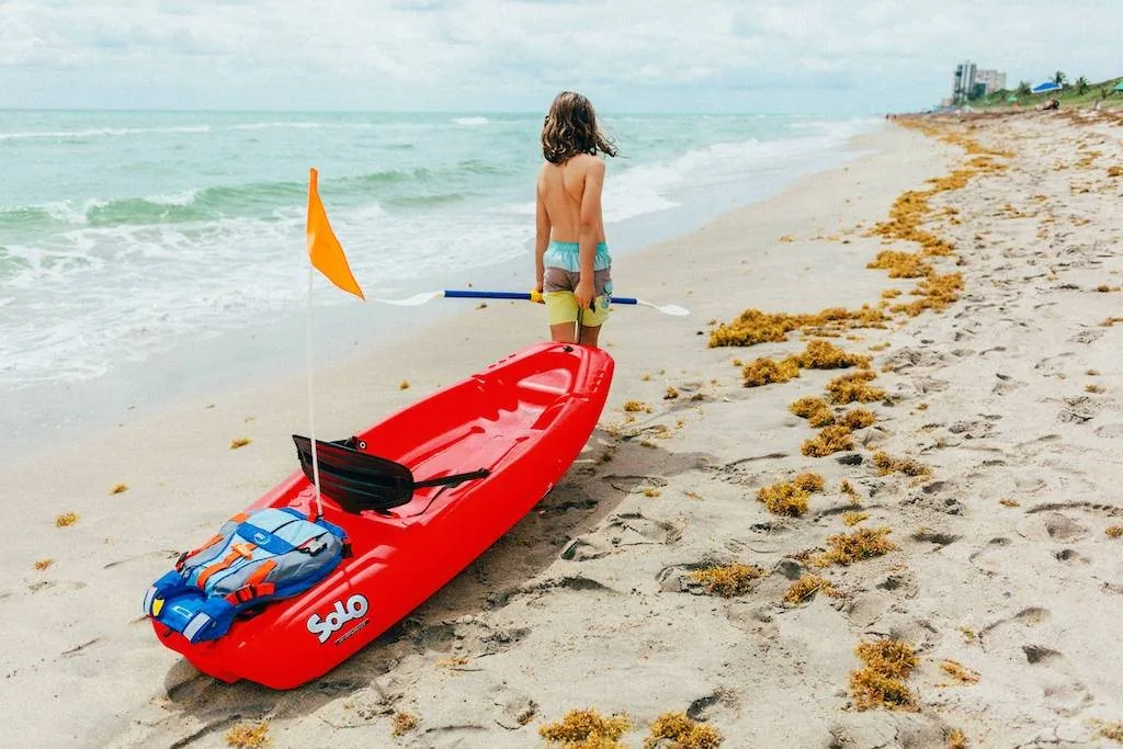 Child pulling a kids' kayak along the beach