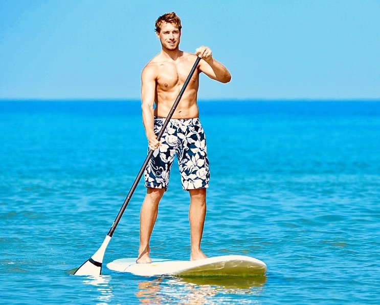 Man stand-up paddleboarding on clear blue water