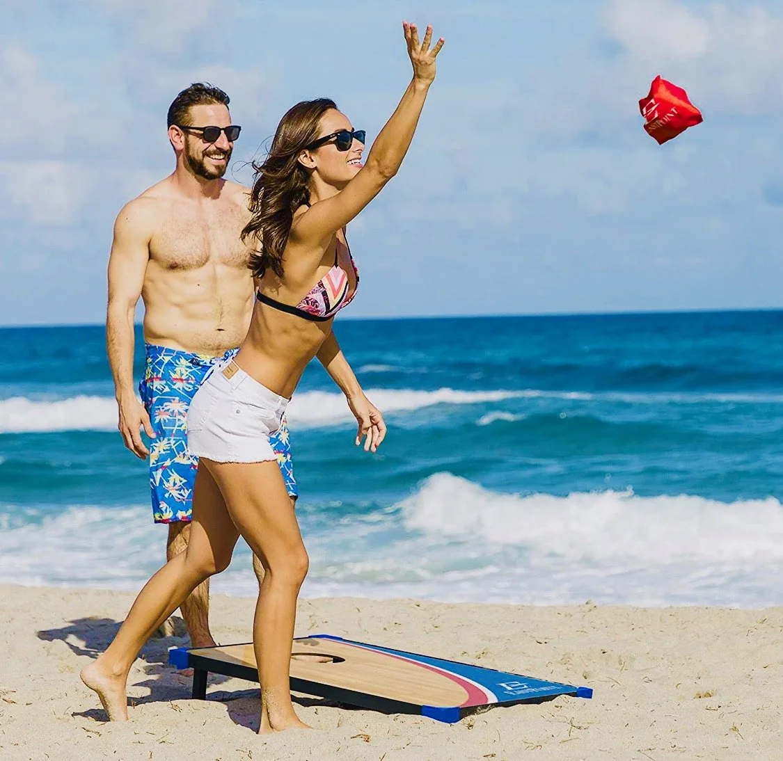 Couple playing Bean Bag Toss by the sea