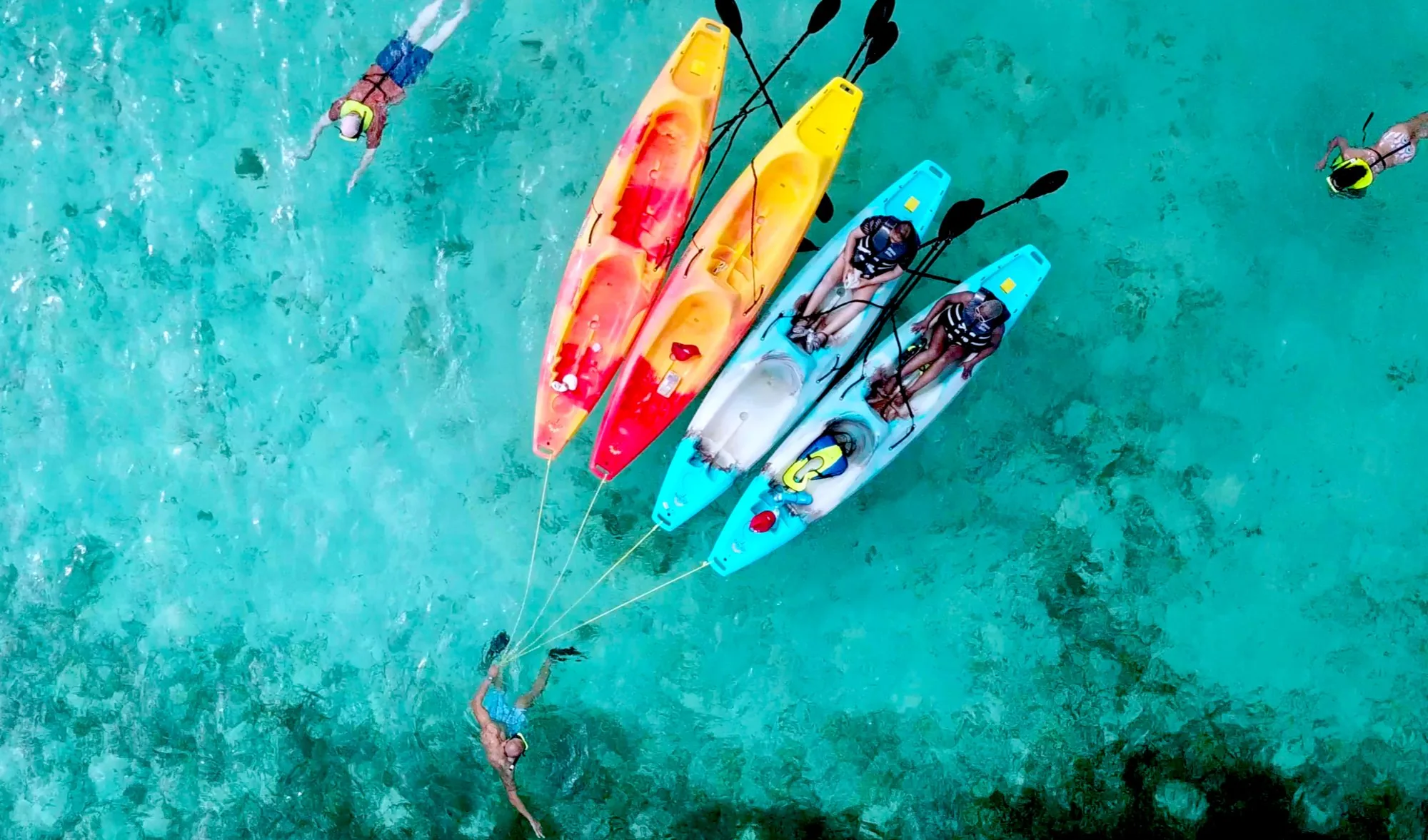 Colourful kayaks seen from above in turquoise water