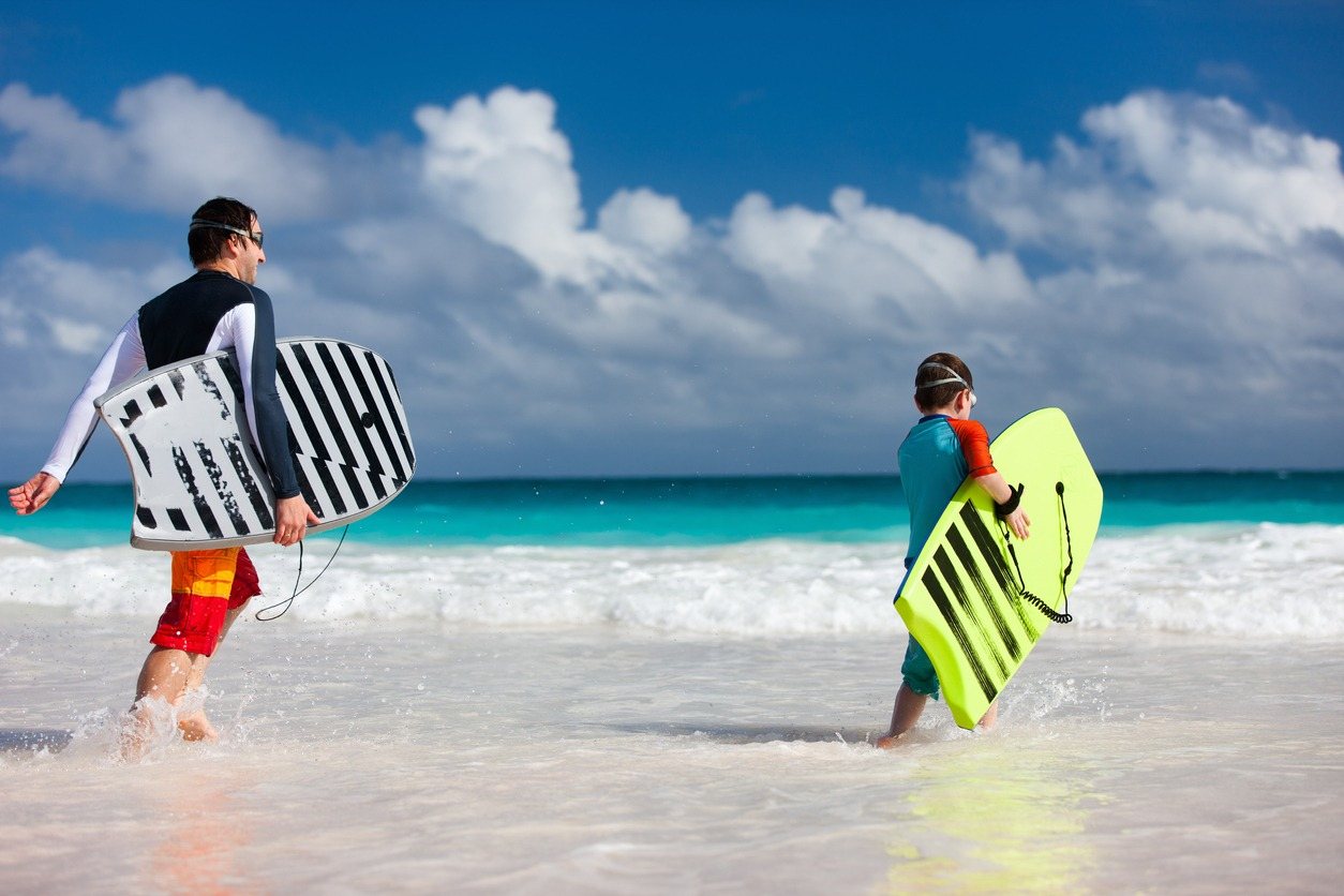 Two boys running into the sea with boogie boards